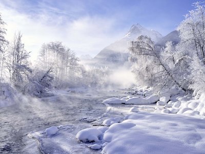 Hotel in Sölden mit 4-Sterne-Service Verschneite Winterlandschaft mit Fluss, nebligen Bäumen und Bergen im Hintergrund