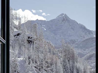 Hotel in Sölden with 4-star service View through an open balcony door of snow-covered mountains and fir trees