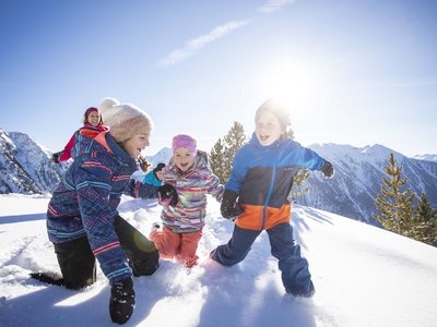 Sölden: Angebote mit vielen Vorteilen Kinder spielen lachend im Schnee auf einem sonnigen Berg mit verschneiten Gipfeln