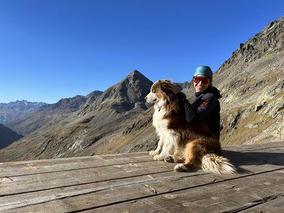 Sunny holiday in Sölden, Austria Hiker with sunglasses and dog on a wooden platform in an alpine mountain landscape