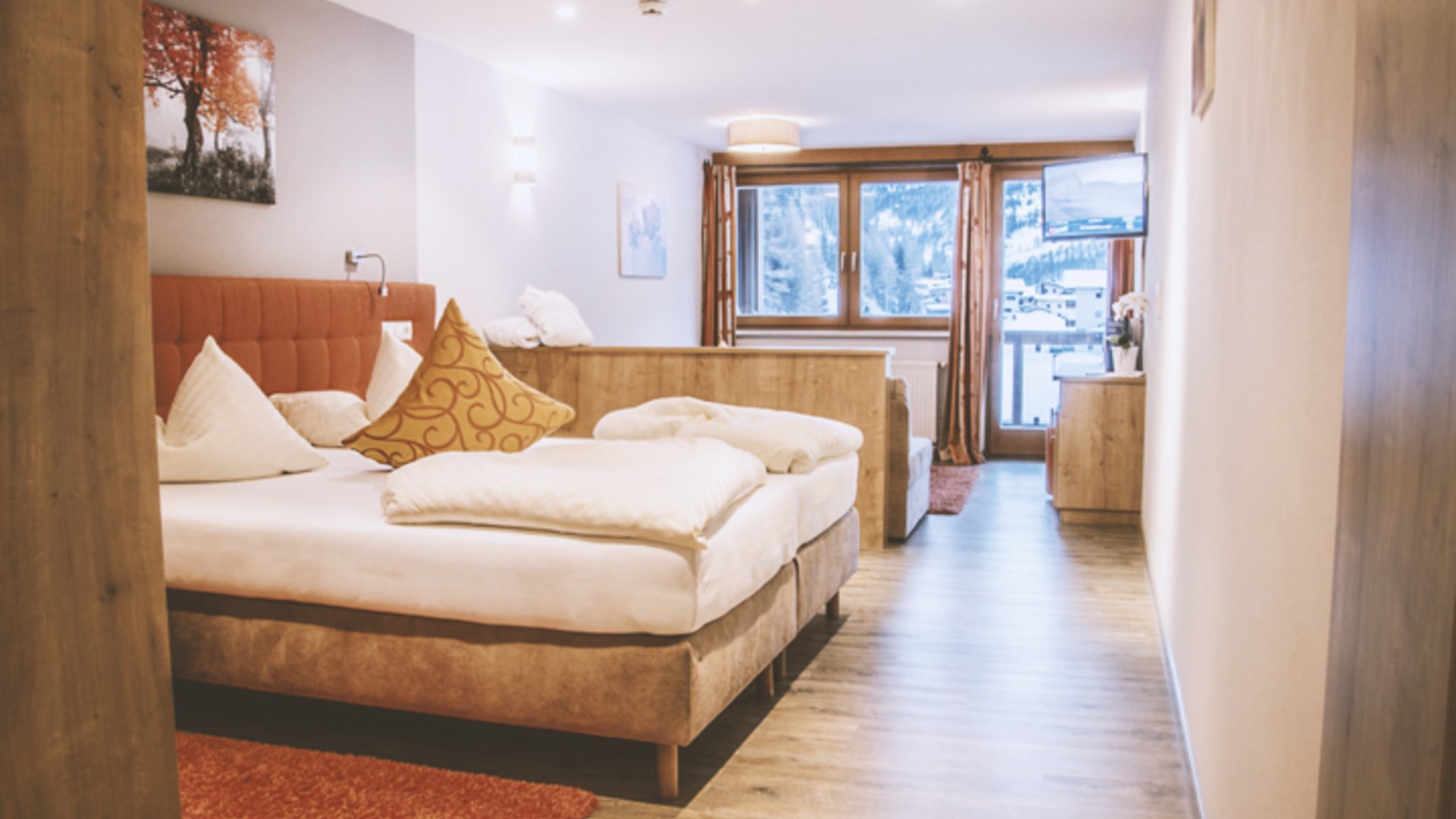 Hotel im Ötztal: erholsamer Schlaf Helles Hotelzimmer mit Doppelbett, Sitzbank, Fernseher und Balkon mit Bergblick