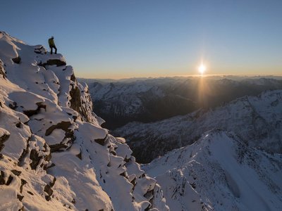 Sölden: Angebote mit vielen Vorteilen Person steht auf schneebedecktem Berggipfel bei Sonnenuntergang