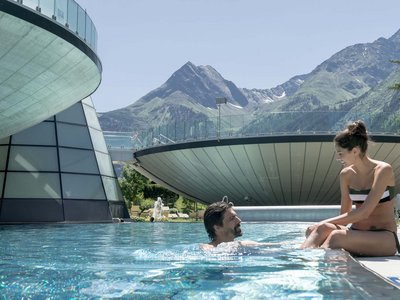 Sölden: Angebote mit vielen Vorteilen Paar entspannt am Pool mit Alpenblick und moderner Architektur im Hintergrund