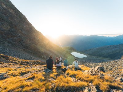 Sunny holiday in Sölden, Austria Four hikers enjoy the sunset overlooking a mountain lake