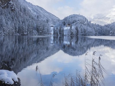 Holiday in Sölden: what’s included Snow-covered mountain lake with reflected pine trees and houses in winter