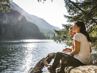 Sunny holiday in Sölden, Austria Couple sitting by a lake with mountains in sunlight