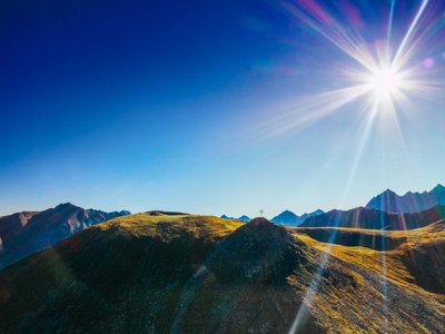 Hotel in Sölden mit 4-Sterne-Service Sonniger Himmel über einem gebirgigen Landschaft mit Gipfelkreuz