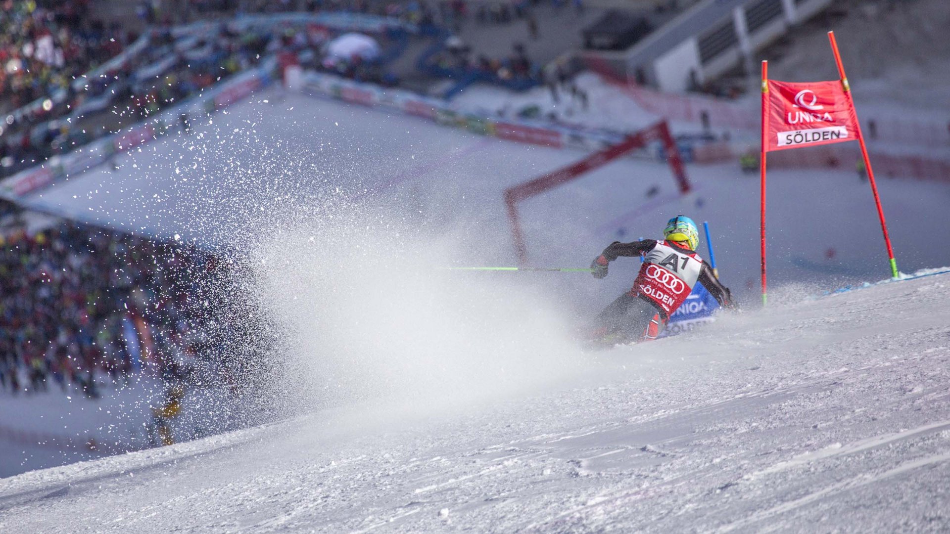 Skiing holiday in Sölden? Come to Hotel Sunny! Skier racing past a red gate in the Sölden ski course with snow spray