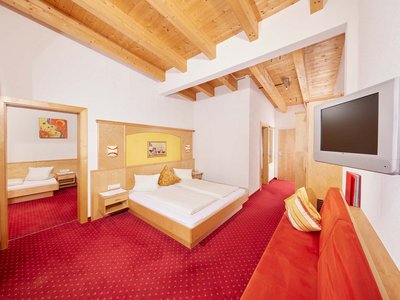 Familienhotel in Sölden: Hotel Sunny Sölden Hotelzimmer mit Doppelbett, Einzelzimmer, rotem Teppich und Holzbalkendecke