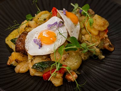Das Restaurant in Sölden im Hotel Sunny Bratkartoffeln mit Spiegelei und Kräutern auf schwarzem Teller