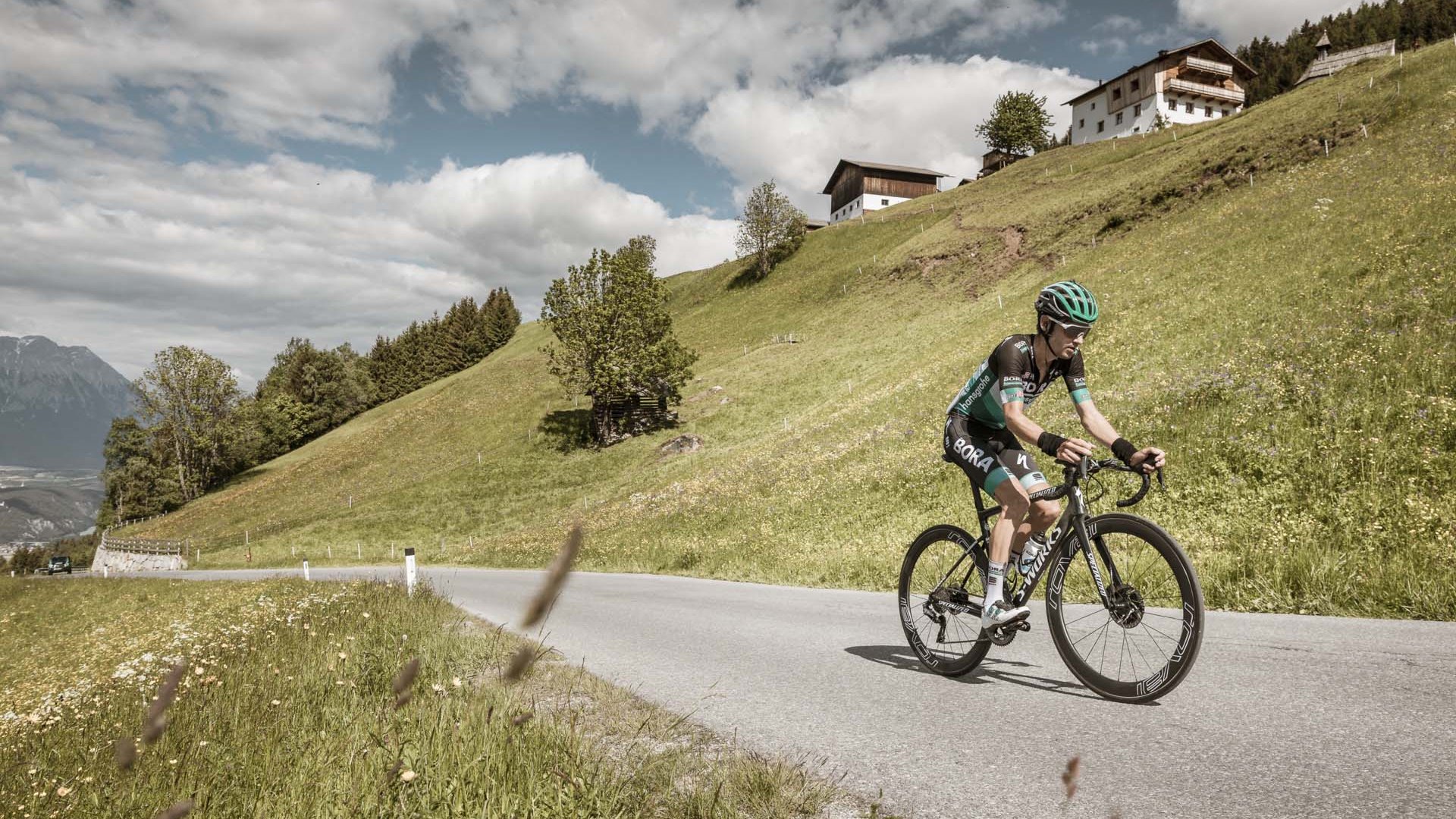 Ausflugsziele in Sölden gesucht? Radfahrer fährt bergauf auf Landstraße mit Hügeln und Häusern im Hintergrund