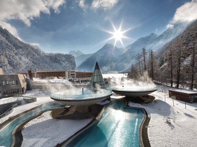 Familienhotel in Sölden: Hotel Sunny Sölden Thermalbäder mit Dampf in verschneiter Alpenlandschaft bei Sonnenlicht