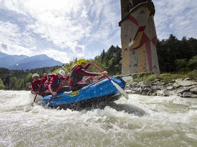 Freizeitarena Sölden und noch viel mehr Gruppe beim Wildwasser-Rafting auf Fluss mit Kletterwand im Hintergrund