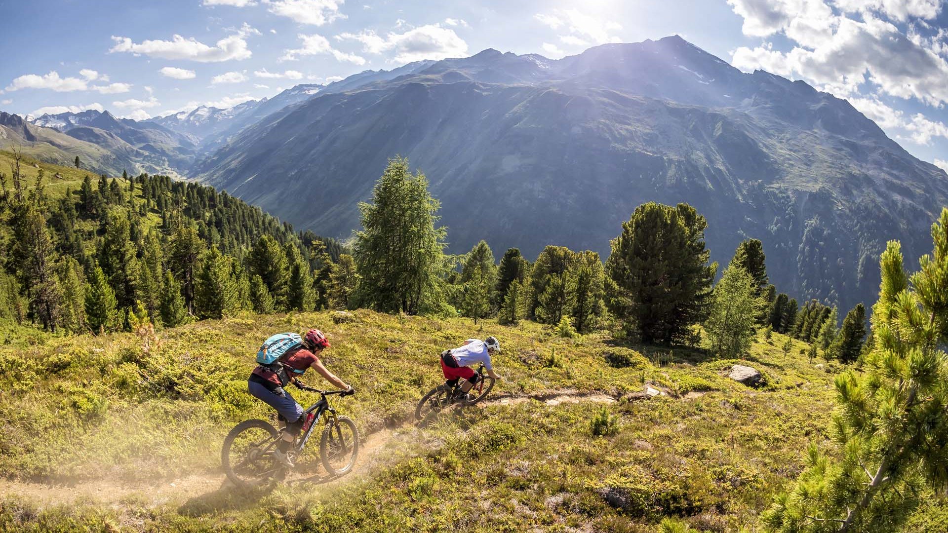 Biking hotel in Sölden: Hotel Sunny Two mountain bikers ride a forest trail in the mountains on a sunny day