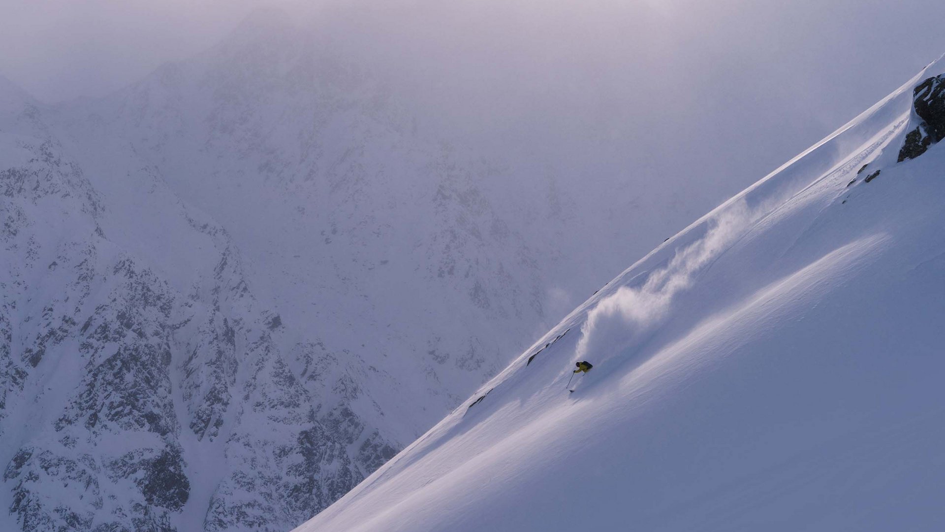 Looking for excursion destinations in Sölden? Skier descending a steep snow-covered mountain slope in foggy conditions.