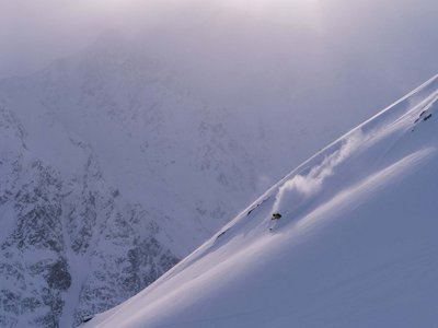 Sunny holiday in Sölden, Austria Skier descending a steep snow-covered mountain slope in foggy conditions.