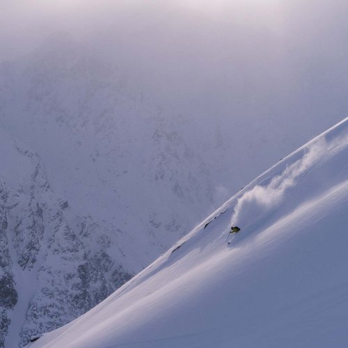 Skiing holiday in Sölden? Come to Hotel Sunny! Skier descending a steep snow-covered mountain slope in foggy conditions.