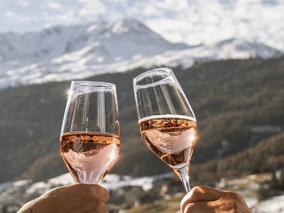 Hotel in Sölden with 4-star service Two people toast with champagne glasses on a balcony overlooking snowy mountains