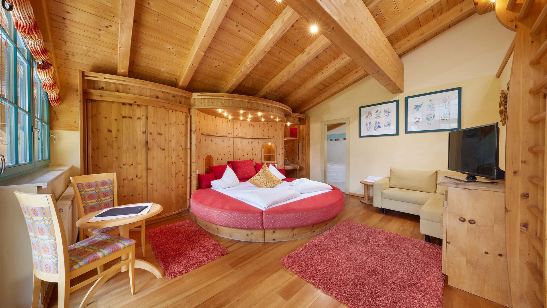 Dein 4-Sterne-Hotel im Ötztal Gemütliches Hotelzimmer mit Rundbett, Holzmöbeln und roten Teppichen