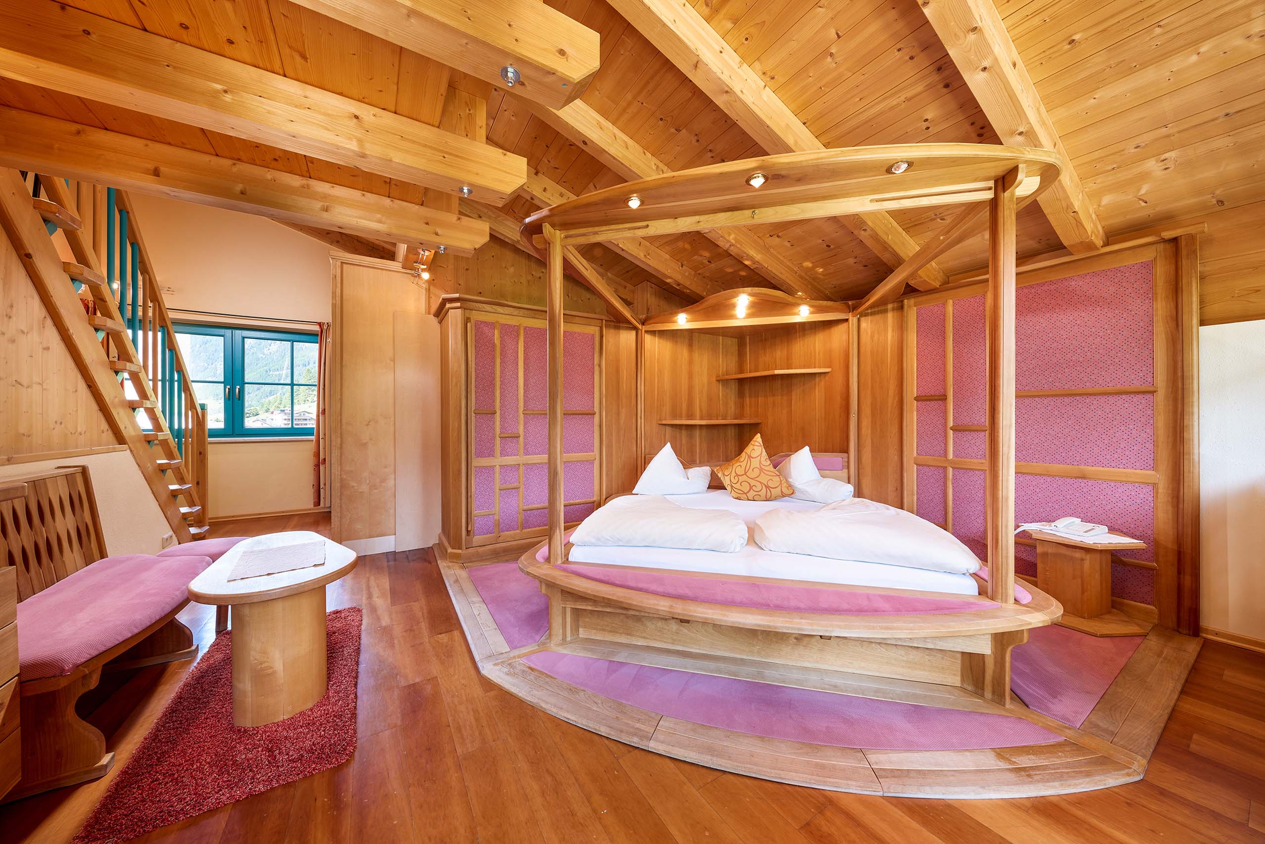 Hotel im Ötztal: erholsamer Schlaf Gemütliches Schlafzimmer mit Holzdecke und rundem Himmelbett mit rosa Akzenten